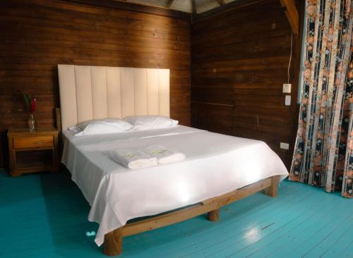 卡普兰干Hotel Bahía Aguacate的卧室配有一张白色大床和木墙