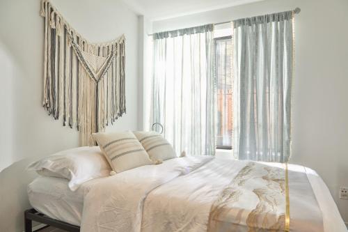 纽约American Dream Guest House的一间卧室配有一张带白色床单的大床和大窗户