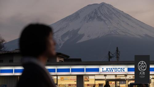 富士河口湖汤雾富士之宿 大池酒店的站在一座建筑物后面的山前行走的人