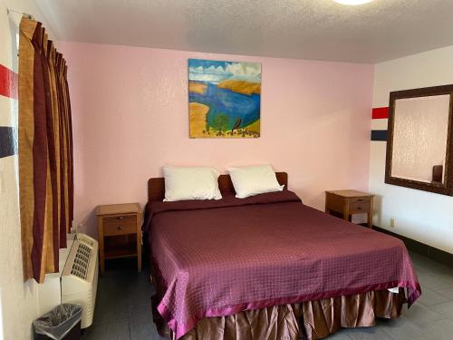 奥克兰Laurel Inn的卧室配有一张床,墙上挂有绘画作品