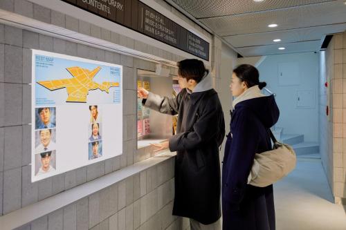 首尔Aank Hotel Seoul Sinchon的两个人看着墙上的海报