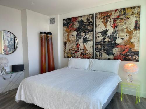 圣地亚哥Massive Penthouse Overlooking All of San Diego的卧室配有白色的床和墙上的绘画作品