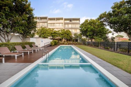 尼尔森湾Oaks Nelson Bay Lure Suites的一个带椅子的游泳池和一个背景建筑