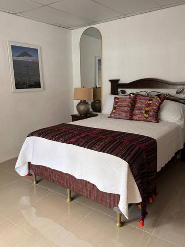 危地马拉安地瓜Casa Geranios Antigua的一间卧室配有一张大床和镜子