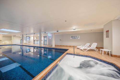 悉尼Oaks Sydney Castlereagh Suites的一个带两把椅子的大型游泳池