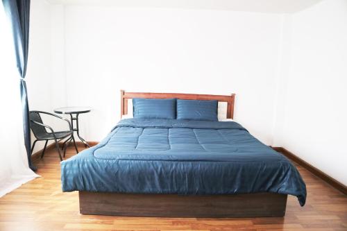 Lak SiHappyhouse Laksi station (PK14)的一间卧室配有一张带蓝色床单的床和一张桌子。