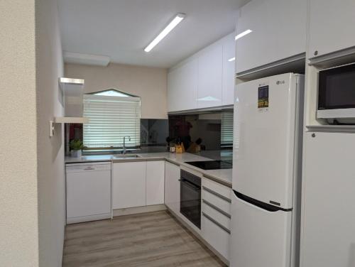 拜伦湾拜伦湾海滨公寓的厨房配有白色橱柜和白色冰箱。