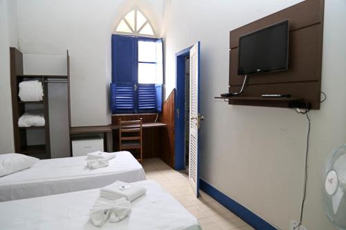 马里亚纳普罗维登西亚酒店的一间设有两张床和一台墙上电视的房间
