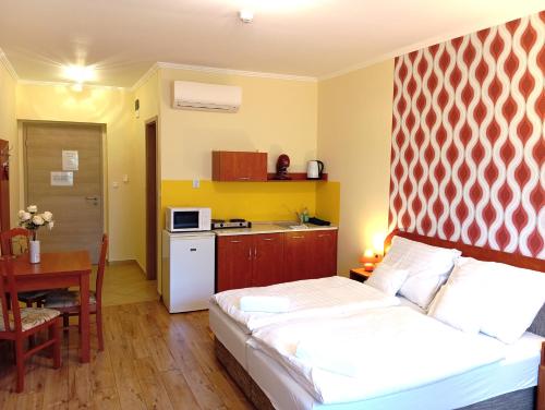 博加奇Patak-Party Apartmanok的一间卧室配有一张床,厨房配有桌子