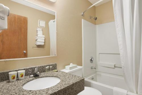 马塞纳马塞纳NY速8酒店的浴室配有盥洗盆、卫生间和浴缸。