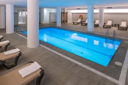 萨洛Golden Acqua Salou的游泳池位于酒店客房内,配有桌椅