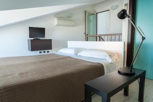 里米尼克里斯塔罗酒店的一间卧室配有一张床和一张带台灯的桌子