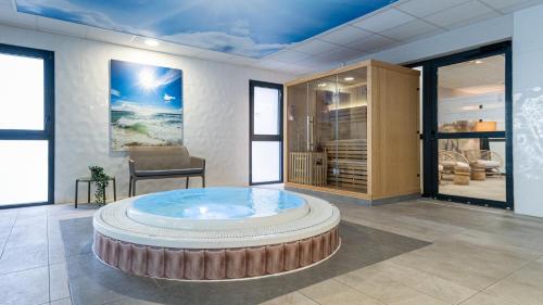 滨海迪沃Kyriad Prestige Residence & Spa Cabourg-Dives-sur-Mer的一间位于中间的大型客房,配有热水浴缸。