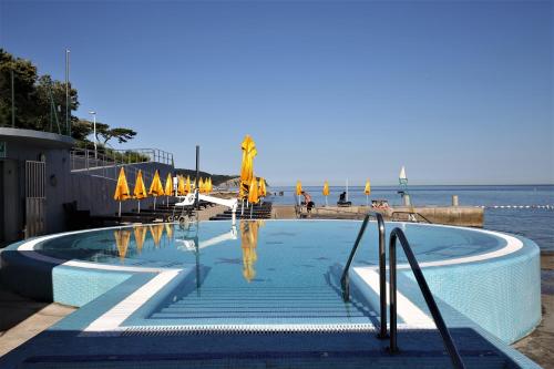 伊佐拉Depandansa Vista Parco, Izola的毗邻大海的带遮阳伞的游泳池