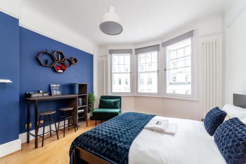 伦敦Cannon Street Studios的一间卧室设有蓝色的墙壁、一张床和一张书桌