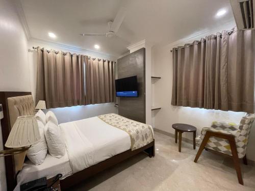 新德里Wongdhen House的一间卧室配有一张床、一台电视和一把椅子