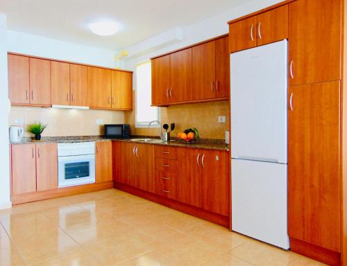 罗萨里奥港Brisa Del Mar Fuerteventura的厨房配有木制橱柜和白色冰箱。
