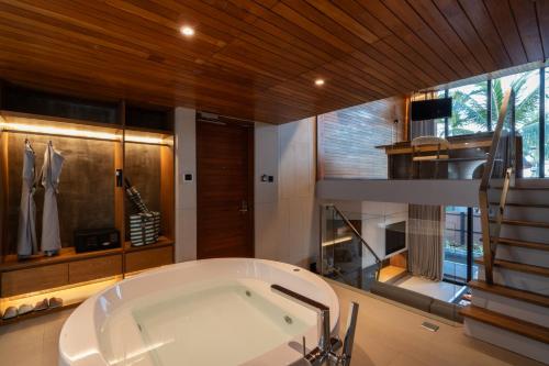蔻立Casa De La Flora - SHA Extra Plus的带浴缸和楼梯的大型浴室
