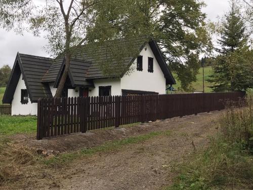 韦特利纳Szczęśliwy Domek的铁栅后面有黑色屋顶的白色房子