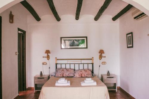 NigüelasHotel Rural Alqueria de los lentos的一间卧室配有一张带两张桌子和两条毛巾的床。