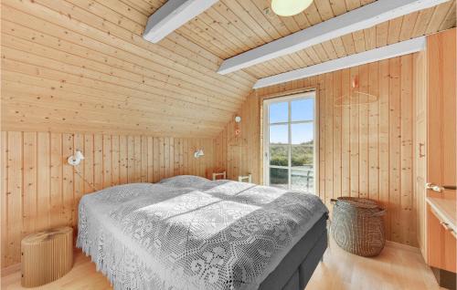 Nørre LyngvigBeautiful Home In Ringkbing With Wifi的木制客房内的一间卧室,配有一张床