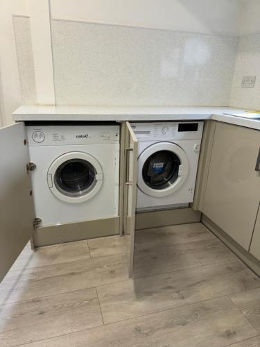 卡迪夫Cardiff Grangetown Stylish 3Bed House.的洗衣房,在柜台下配有洗衣机和烘干机