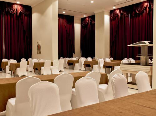 麦加فنادق رزون المسك مكة المكرمة的一间设有白色椅子和桌子以及红色窗帘的房间