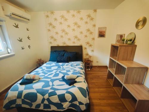 圣路易Chambre climatisée cosy Auberge du Manala Hôtel 24-24的一间卧室配有一张带蓝色和白色棉被的床
