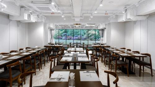 首尔The Prima Hotel Jongno的一间带桌椅的用餐室和大窗户