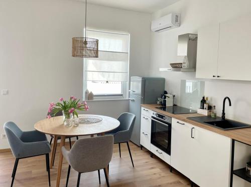 滨湖默尔比施Pannonia Apartments的一间带桌椅的厨房和一间带白色橱柜的厨房