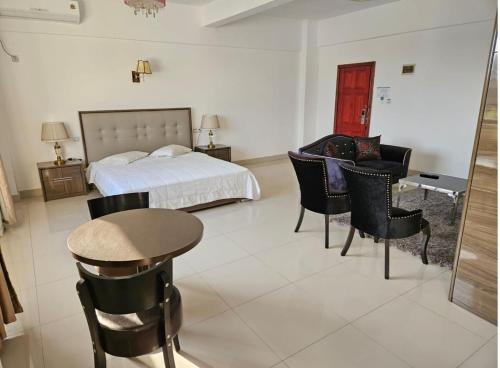 罗安达Hotel Kilimanjaro - Luanda Angola的卧室配有一张床和一张桌子及椅子
