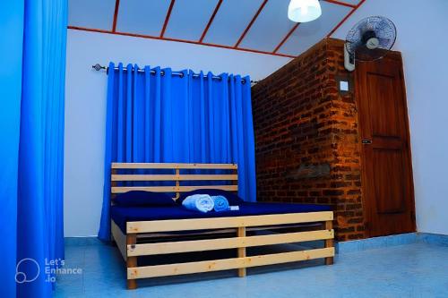 安帕赖Mereiyans Village Villa的一间卧室配有一张带蓝色窗帘和砖墙的床。