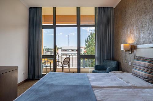 圣安德烈VILA PARK Nature & Business Hotel的酒店客房设有一张床和一个大窗户