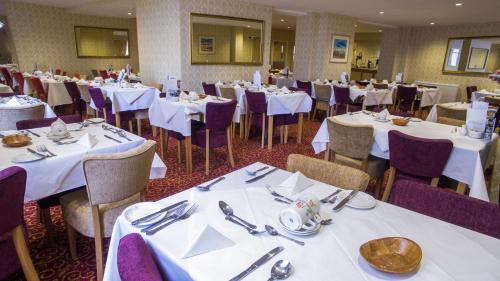 大雅茅斯新滩大酒店的一间设有白色桌子和紫色椅子的用餐室
