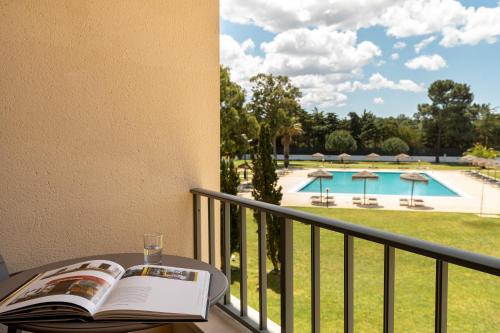 圣安德烈VILA PARK Nature & Business Hotel的享有泳池美景的阳台上的书