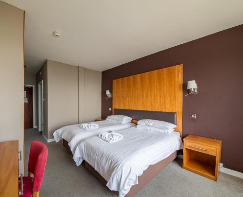 尚克林尚克林酒店的一间卧室配有两张带白色床单的床