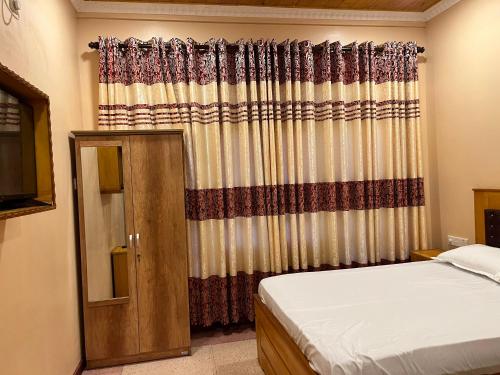贾夫纳Palm Path Resort的一间卧室配有床和带窗帘的窗户