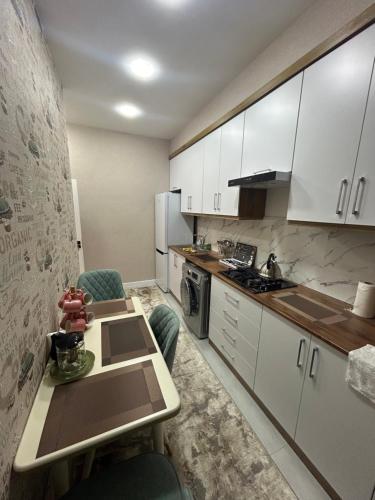 撒马尔罕Apartment for tourists的厨房配有白色橱柜和桌椅