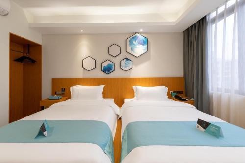 广州希岸·轻雅酒店(广州芳村花地湾地铁站店)的酒店客房设有两张床和窗户。