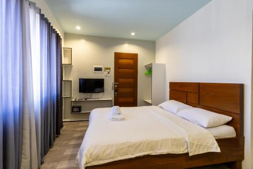 杜马格特Kayong's Inn的一间卧室配有一张大床和电视