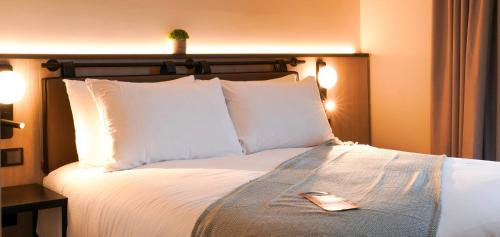 East BarnetSouthgate Hotel London的一张带白色枕头的床和遥控器