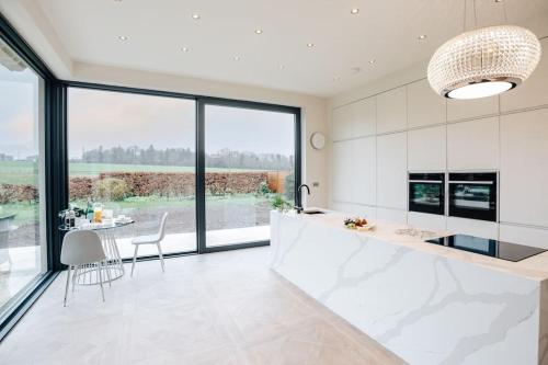 BuckinghamshireWisteria House - Sleeps 11的厨房配有白色橱柜和桌椅