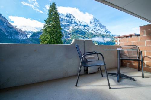 格林德尔瓦尔德Hotel Grindelwalderhof的山景阳台上配有两把椅子和一张桌子