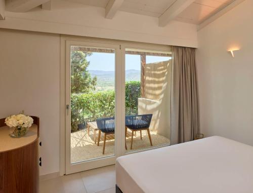 奇亚Baia Di Chia Resort Sardinia, Curio Collection By Hilton的一间卧室设有一张床和一个滑动玻璃门