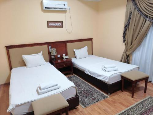 布哈拉Sarbon Plaza Hotel的带窗户的客房内设有两张单人床。