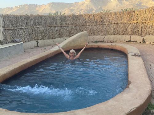 Al QaşrBeir El Gabal Hotel (with Hot Springs)的把冲浪板放在游泳池里的女人