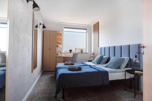波兹南Sapphire Room Hotel Lechicka的一间卧室配有一张带蓝色床单的床和一扇窗户。