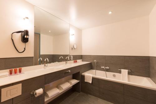 阿姆斯特丹Leonardo Hotel Amsterdam Rembrandtpark的一间带两个盥洗盆和大镜子的浴室