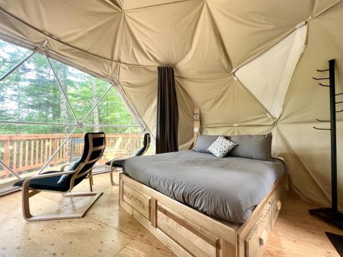 圣加布里尔德瓦尔卡捷Vallée Jeunesse Québec的一间卧室配有一张床铺,帐篷内提供一把椅子