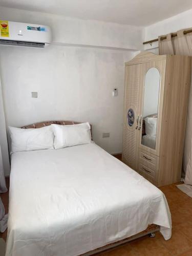 特马The Lord's residence的卧室配有白色的床和木制橱柜。